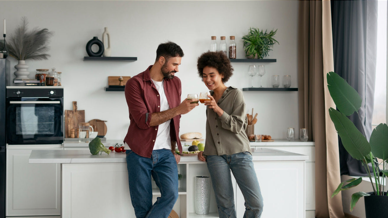 Man and woman standing in a modern kitchen, holding hands.